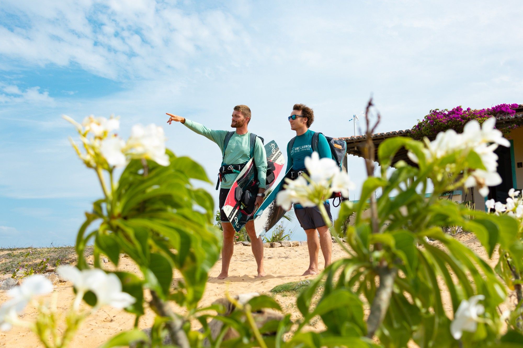 Pierre et Philippe Ancelin sur la dune, planches sous le bras, Pierre montre le spot du doigt